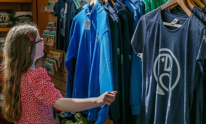 Young girl looking through display of branded clothing in shop